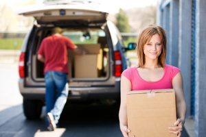 woman with car carrying boxes to storage unit